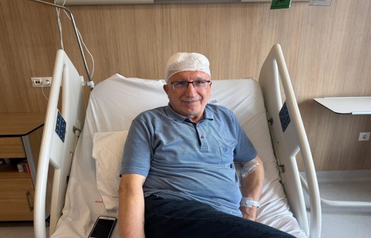 Parkinson hastası Ekrem Karanfil, hastane yatağında başı sargılı şekilde oturuyor.