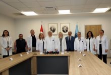Akdeniz Üniversitesi Rektörü Prof. Dr. Özlenen Özkan ve Organ Nakli Enstitüsü Müdürü Prof. Dr. Ömer Özkan, düzenlenen basın toplantısı odasında diğer hocalar ile beraber poz veriyor.