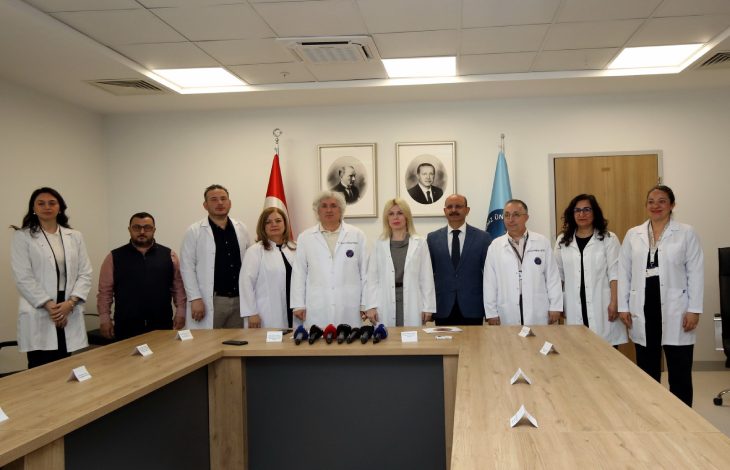 Akdeniz Üniversitesi Rektörü Prof. Dr. Özlenen Özkan ve Organ Nakli Enstitüsü Müdürü Prof. Dr. Ömer Özkan, düzenlenen basın toplantısı odasında diğer hocalar ile beraber poz veriyor.