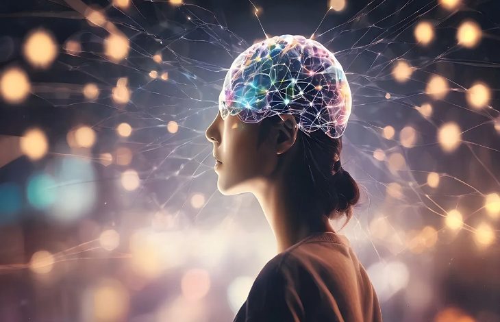 Görselde profilden görülen bir kadın silueti yer alıyor. Kadının baş kısmında, beyin bölgesi renkli ışıklar ve birbirine bağlanan sinir ağlarını andıran çizgilerle dijital şekilde betimlenmiş. Arka planda ise parlayan noktalar ve ışık efektleri bulunuyor; bu da beynin çalışmasını, sinir bağlantılarını ve teknoloji-nörobilim ilişkisini simgeleyen futuristik bir atmosfer oluşturuyor.
