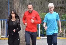 Açık alanda çekilmiş fotoğrafta üç kişi birlikte koşuyor. Ortada kırmızı eşofman üstü giyen bir yetişkin erkek, iki yanında ise spor kıyafetli gençler var. Soldaki siyah eşofmanlı genç kadın, sağdaki ise mavi tişörtlü genç erkek. Park benzeri bir ortamda, ağaç ve korkulukların bulunduğu bir alanda antrenman yaparken görüntülenmişler.