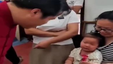 Görselde yer alan yaşlı bir kadının kucağında oturan çocuk ve çocuğunun önünde onu muayene eden doktor yer alıyor.