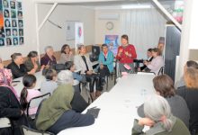 Diş Hekimi Nurhan Çelik Demir, masalarda oturan vatandaşlara ayakta durarak konuşma yapıyor.