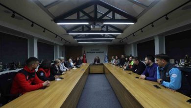 Uzun bir toplantı masasının etrafında toplanmış katılımcılar, resmi bir toplantı yapıyor. Masanın başında bir yetkili otururken, iki yanda farklı kurumlardan gelen kişiler dikkatle dinliyor. Ortam, belediyeye ait bir toplantı salonunu andırıyor ve ciddi bir çalışma atmosferi hâkim.