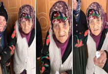 Görselde, üç kareden oluşan bir kolaj yer alıyor. Başörtülü, yaşlı bir kadın her karede kapı önünde görülüyor. Üzerinde desenli bir hırka ve yelek, başında renkli bir yazma bulunuyor. Kadın, bazen doğrudan kameraya bakıyor, bazen de elindeki kağıdı uzatıyor gibi görünüyor. Arka planda başka bir yaşlı kadın da yer alıyor. Fotoğraflar, samimi bir mahalle ortamında çekilmiş gibi duruyor.