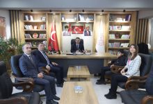 Bir makam odasında çekilen fotoğrafta, İl Millî Eğitim Müdürü masanın arkasında otururken karşısında iki erkek, bir kadın ve bir çocuk koltuklarda oturarak poz veriyor. Odada Türk bayrağı, resmi bayraklar, kitaplıklar ve duvarda Mustafa Kemal Atatürk ile Recep Tayyip Erdoğan’ın portreleri yer alıyor. Ortadaki sehpalarda su şişeleri bulunuyor ve ziyaret resmi bir görüşme havasında gerçekleşiyor.