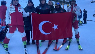 Otizm Kayak Milli Takımımız ve antrenörler Türk bayrağı açarak yarışma alanında poz veriyor.