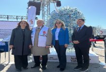 Fotoğrafta açık alanda düzenlenen bir etkinlikte dört kişi yan yana durarak poz veriyor. Arkalarında plastik şişelerden oluşturulmuş büyük bir böbrek maketi yer alıyor. Etkinlik alanında pankartlar ve stantlar bulunurken, ortam böbrek sağlığına dikkat çekmek amacıyla düzenlenen bir farkındalık çalışmasını yansıtıyor.