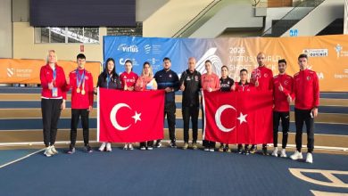Fotoğrafta kapalı bir spor salonunda toplu halde poz veren sporcular ve antrenörler görülüyor. Sporcuların çoğu kırmızı Türkiye yazılı eşofmanlar giymiş. Grubun ortasında iki kişi büyük Türk bayrakları tutuyor. Bazı sporcuların boynunda kazandıkları madalyalar bulunuyor. Arka planda “2026 Virtus World Short Track Championship” yazılı bir organizasyon panosu yer alırken, sporcular ve teknik ekip kamera karşısında takım halinde gururla poz veriyor.