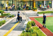İllüstrasyonlu görselde, modern bir binanın önünde yer alan **engelsiz ve erişilebilir şekilde tasarlanmış bir açık alan** görülmektedir; rampalar ve sarı yönlendirme yolu sayesinde tekerlekli sandalye kullanan bireyler rahatça hareket ederken, bazı insanlar bahçede oturup sohbet etmekte ve bir kişi de yan taraftaki spor alanında top oynamaktadır.
