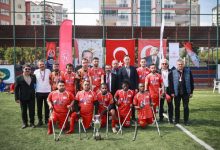 Anadolu Erciyes Engelliler Spor Kulübü sporcuları, yöneticiler kazanılan kupayla sahada poz veriyor.