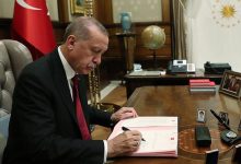Cumhurbaşkanı Recep Tayyip Erdoğan makamındaki masada oturmuş imza atıyor.