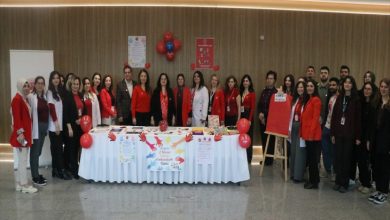 Dünya Otizm Farkındalık Günü kapsamında İzmir Şehir Hastanesi’nde açılan stantta doktorlar, personel ve katılımcılar toplu poz veriyor.