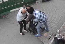 Güvenlik kamerası açısından çekilmiş görüntüde, üç kişi küçük bir çocuğun etrafında toplanmış durumda. Yetişkinlerden biri çocuğa müdahale ederken diğerleri destek oluyor. Kaldırım kenarında geçen bu an, acil bir duruma yapılan hızlı müdahaleyi yansıtıyor.