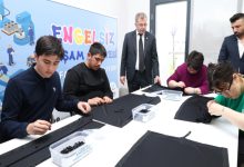 Osmangazi Belediye Başkan Yardımcısı Mücahit Yıldızhan, ayakta durarak perde dikimi yapan engelli bireyleri izliyor.