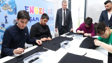 Osmangazi Belediye Başkan Yardımcısı Mücahit Yıldızhan, ayakta durarak perde dikimi yapan engelli bireyleri izliyor.