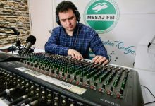 Radyocu Muhammed Emirhan Güngör, kulaklık takmış radyo stüdyosunda büyük bir ses mikseri üzerinde dikkatle ayar yaparken görülüyor.