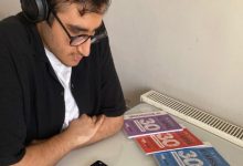 Görme engelli Ömer Miraç Şahin sırada oturuyor ve önünde üç tane EKPSS kitapçığı bulunuyor.