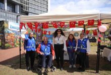 EngelsizFest: Üreten Eller Kermesi standı önünde, Türk bayraklarıyla süslenmiş tentesi altında poz veren görevliler ve katılımcılardan oluşan 5 kişilik bir gruptur. Etkinlikteki dayanışma atmosferini yansıtmaktadır.
