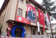 Bir kamu binasının dış cephesinde Türk bayrakları ve Mustafa Kemal Atatürk posterleri asılı görülüyor. Giriş kısmı mavi balonlarla süslenirken, binanın üzerinde “Kavacık Engelli Aktif Yaşam Merkezi Müdürlüğü” tabelası yer alıyor. Görsel, resmi açılış ya da etkinlik atmosferini yansıtıyor.
