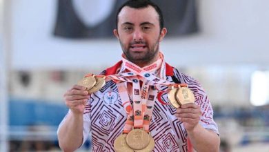 Milli sporcu Alper Öztürk, boynunda bulunan kazandığı madalyaları tutarak poz veriyor.