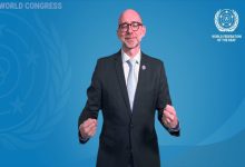 Mavi arka plan önünde takım elbiseli ve gözlüklü bir kişi, el hareketleriyle işaret dili kullanırken görülüyor. Görselde Dünya Sağırlar Federasyonu (WFD) logosu ve “World Congress” yazısı yer alıyor.