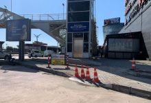 Yaya üst geçidinin yanında bulunan asansör kulesi önünde sürdürülen kaldırım ve yol çalışması görülüyor. Çalışma alanı trafik konileri ve uyarı levhalarıyla çevrilirken, bölgede erişilebilirlik düzenlemelerine yönelik çalışmalar dikkat çekiyor.