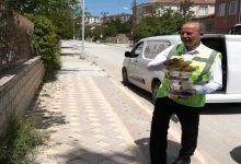 Açık yeşil üniformalı belediye personeli erkek, beslenme gıdalarını elinde taşıyor.