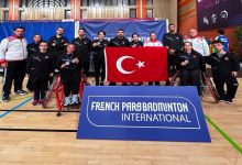 Turnuvaya katılan Para Badminton Milli Takımı ve teknik heyet, Türk Bayrağı açarak poz veriyor.