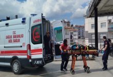 Bir ambulansın yanında sağlık ekiplerinin sedye üzerindeki yaralı bir kişiye müdahale ettiği görülüyor. Acil sağlık personeli, yaralıyı ambulansa taşımaya hazırlanırken olayın bir sağlık kuruluşu veya hastane çevresinde gerçekleştiği anlaşılıyor. Görsel, trafik kazası sonrası yürütülen acil müdahale sürecini yansıtıyor.