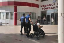 Görselde bir yükseköğretim kurumu girişinde iki polis memuru, tekerlekli sandalyedeki bir öğrenciye eşlik ediyor. Öğrenci bina girişine doğru yönlendirilirken arka planda sınav merkezi atmosferi görülüyor. Kare, erişilebilirlik ve destek anını yansıtıyor.