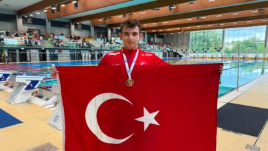 Özel Sporcu Bilge Kağan Yılgın, boynunda madalyası ve elinde Türk bayrağı tutarak poz veriyor.