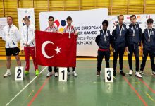 Özel sporcular Burak Burç ve Efe Gümüş, Türk bayrağı tutarak madalya töreninde rakiplerinin yanında poz veriyor.