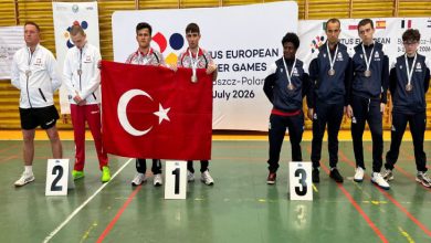 Özel sporcular Burak Burç ve Efe Gümüş, Türk bayrağı tutarak madalya töreninde rakiplerinin yanında poz veriyor.