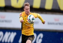 Runavik forması giyen sağ kolu ampute futbolcu Marius Lindh, göğsünün önünde top sürüyor.