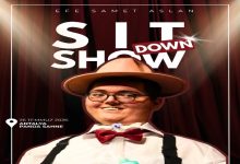 Görselde, kırmızı tiyatro perdesi fonu önünde şapka, papyon ve askılı kıyafet giyen bir kişi gülümseyerek poz veriyor. Afişte "Sit Down Show" başlığı, gösterinin 26 Temmuz 2026'da Antalya Panda Sahne'de gerçekleştirileceği bilgisi yer alırken, sahne ışıkları ve tasarım gösteri atmosferini yansıtıyor.