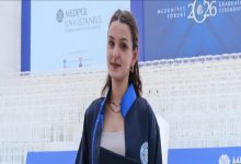 Görselde, mezuniyet cübbesi ve diplomasıyla poz veren genç bir kadın yer alıyor. Arka planda "2026 Mezuniyet Töreni" yazılı sahne, İstanbul Medipol Üniversitesi logosu ve tören alanındaki beyaz sandalyeler görülüyor. Kadın kameraya gülümseyerek bakarken, mezuniyet töreni atmosferi öne çıkıyor.