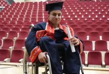 Fotoğrafta, tekerlekli sandalye kullanan Abdullah mezuniyet cübbesi ve kepiyle üniversite amfisinde oturuyor. Elinde diplomasını tutan Abdullah'ın arka planında kırmızı koltuklarla dolu konferans salonu görülüyor.