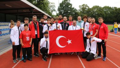 İşitme Engelliler Atletizm Takımı Milli Sporcuları, teknik kadro ile Türkiye İşitme Engelliler Spor Federasyonu Başkanı Dursun Gözel pistte Türk bayrağı tutarak poz veriyor.
