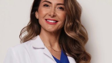 Doç. Dr. Ebru Zülfikaroğlu, beyaz hekim önlüğü ve mavi üstüyle profesyonel bir duruş sergileyen, uzun dalgalı kahverengi saçlara sahip bir kadın sağlık profesyoneli olarak görünüyor. Arka planın sade ve açık tonlarda olması, portreyi daha da öne çıkarıyor ve kendisinin uzmanlık alanını yansıtan güven veren bir ifade oluşturuyor.