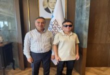 Görme engelli öğrenci Taha Gül, Tokat Gaziosmanpaşa Üniversitesi Rektörü Prof. Dr. Fatih Yılmaz ile beraber yan yana poz veriyor.