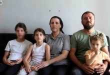 Ayşegül, annesi, babası ve iki kardeşiyle birlikte evde koltukta otururken görülüyor. Aile kameraya doğru bakıyor.