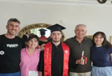 Otizmli Öğrenci Deniz Köse, mezuniyet kıyafetiyle ailesi ile ev ortamında poz veriyor.