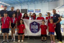 İBB Spor Kulübü Para Yüzme sporcuları ile antrenörler havuz başında poz veriyor.