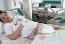 Instagram İçin Alternatif Metin (Kadına Şiddet ve Amputasyon Haberi): Görselin üst bölümünde, hastane odasındaki hasta yatağında yatan ve eşinin saldırısı sonucu iki bacağını da kaybeden mağdur kadın yer alıyor. Beyaz tişört giymiş ve elinde damar yolu/serum kelebeği takılı olan kadın, yastığa yaslanmış biçimde üzgün ve bitkin bir ifadeyle doğrudan objektife bakıyor. Bacak bölgesinde ameliyat sonrası kalın beyaz sargı ve pansuman bezleriyle sarılmış ampute edilmiş uzuv görülüyor; üzerindeki çarşaf ve yastık kılıfında kırmızı T.C. Sağlık Bakanlığı amblemi yer alırken, arka planda odadaki diğer boş hasta yatağı ve tıbbi donanımlar seçiliyor.