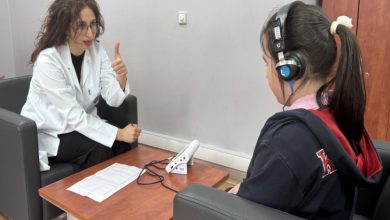 Görselde, klinik veya muayenehane ortamında bir uzman ile çocuk arasında gerçekleştirilen bir işitme testi seansı yer alıyor.