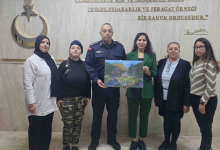 Görselde, kapalı bir mekanda yan yana duran altı kişilik bir grup yer almaktadır. Ortada askeri üniforma giymiş bir erkek ve yanında yeşil takım elbiseli bir kadın, ellerinde manzara resminin yer aldığı bir tabloyu birlikte tutmaktadır. Grubun diğer üyeleri ise onların yanında gülümseyerek poz vermektedir. Arka plandaki duvarda Atatürk'e ait bir yazı ve amblem yer almaktadır.
