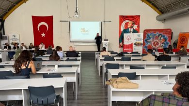 Görselde, Türk bayrakları ve Atatürk posteriyle süslenmiş bir salonda, katılımcıların masa başında oturarak bir konuşmacının sunumunu dinlediği spor ve yaşlılık temalı bir kongre veya eğitim etkinliği görülmektedir.