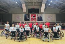 Tekerlekli Sandalye Basketbol Kadın Milli Takımımız önde, teknik heyet arkalarında bulunurken basketbol sahasında poz veriyorlar.