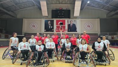 Tekerlekli Sandalye Basketbol Kadın Milli Takımımız önde, teknik heyet arkalarında bulunurken basketbol sahasında poz veriyorlar.